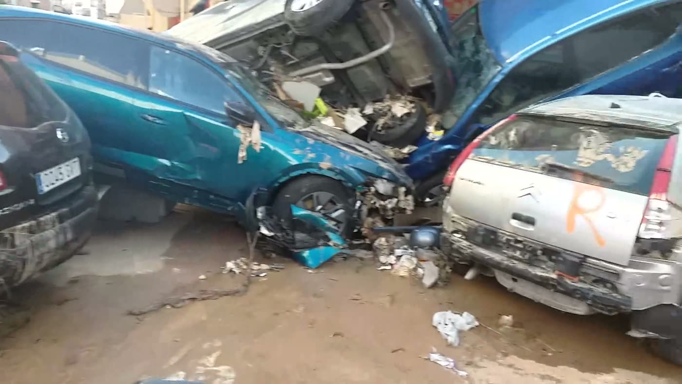 Flood-wrecked cars piled in a muddy street after the water receded.